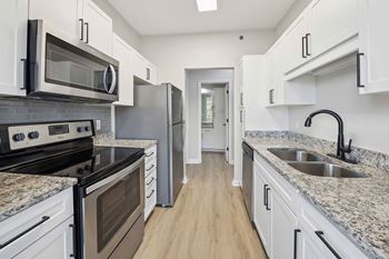 A kitchen with white cabinets and granite countertops.