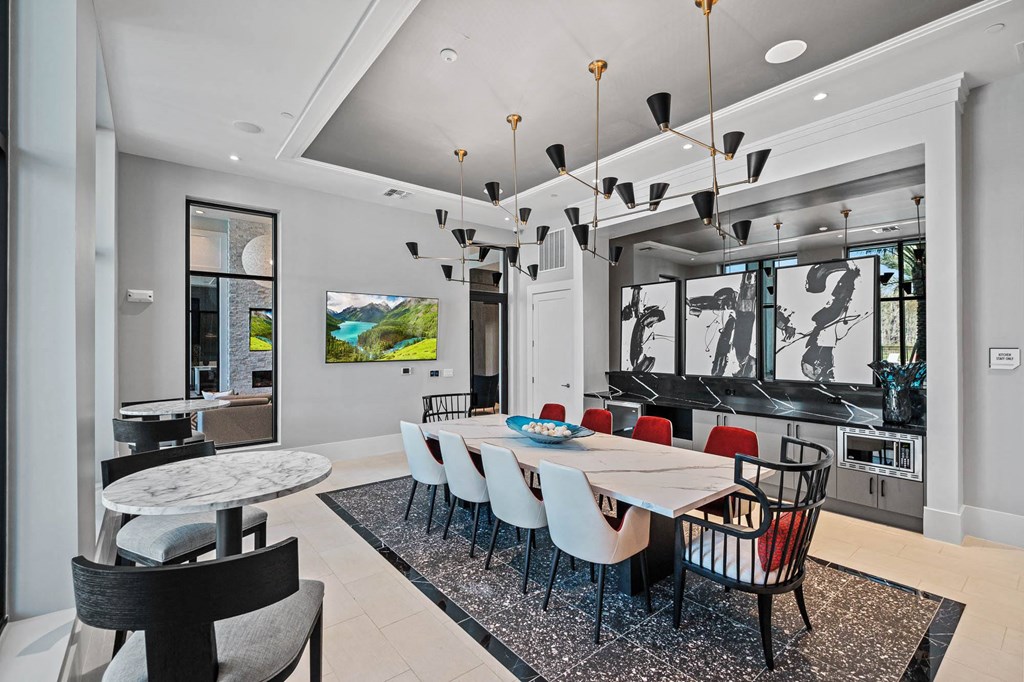 a dining room with a long table and chairs and a living room a dining room with a long table and chairs and a living room at Altis Grand Suncoast, Florida