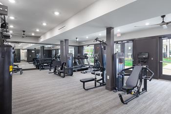 a gym with cardio equipment and weights in a building with windows