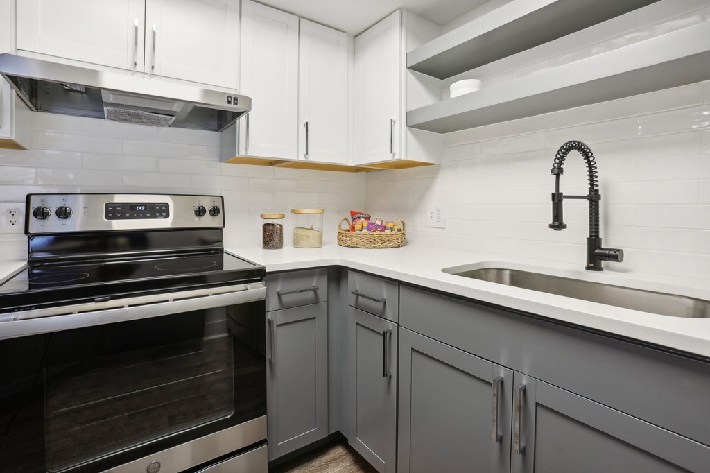 A modern kitchen with a stove, sink, and cabinets.