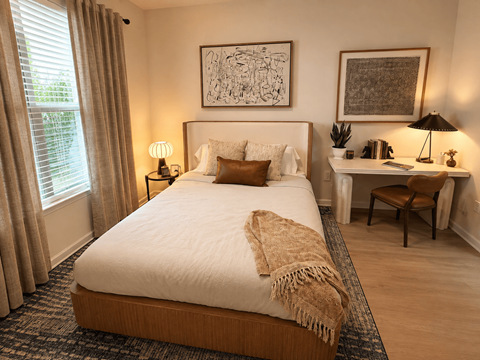 A bedroom with a large bed and a desk with a chair.