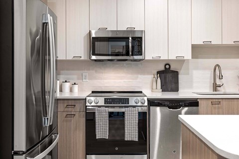 A modern kitchen with a stainless steel refrigerator, microwave, oven, and dishwasher.