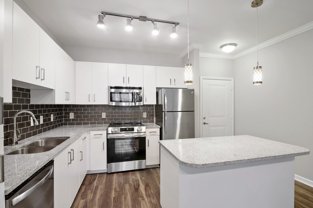 A modern kitchen with white cabinets and stainless steel appliances.