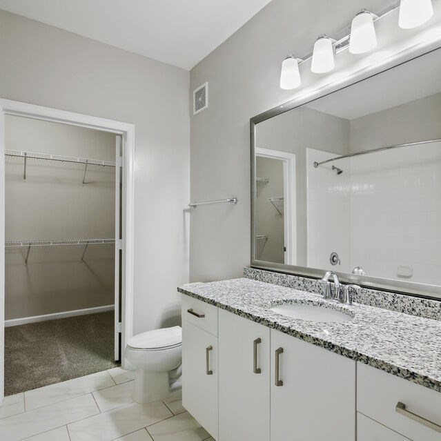 A bathroom with a marble countertop and a large mirror.