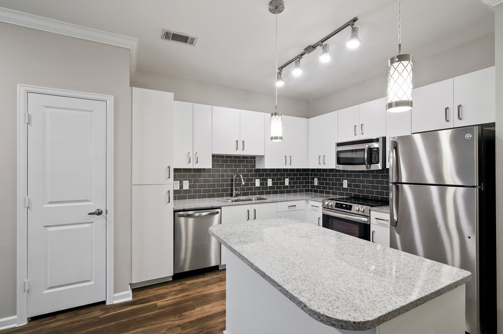 A kitchen with a white counter top and stainless steel appliances.