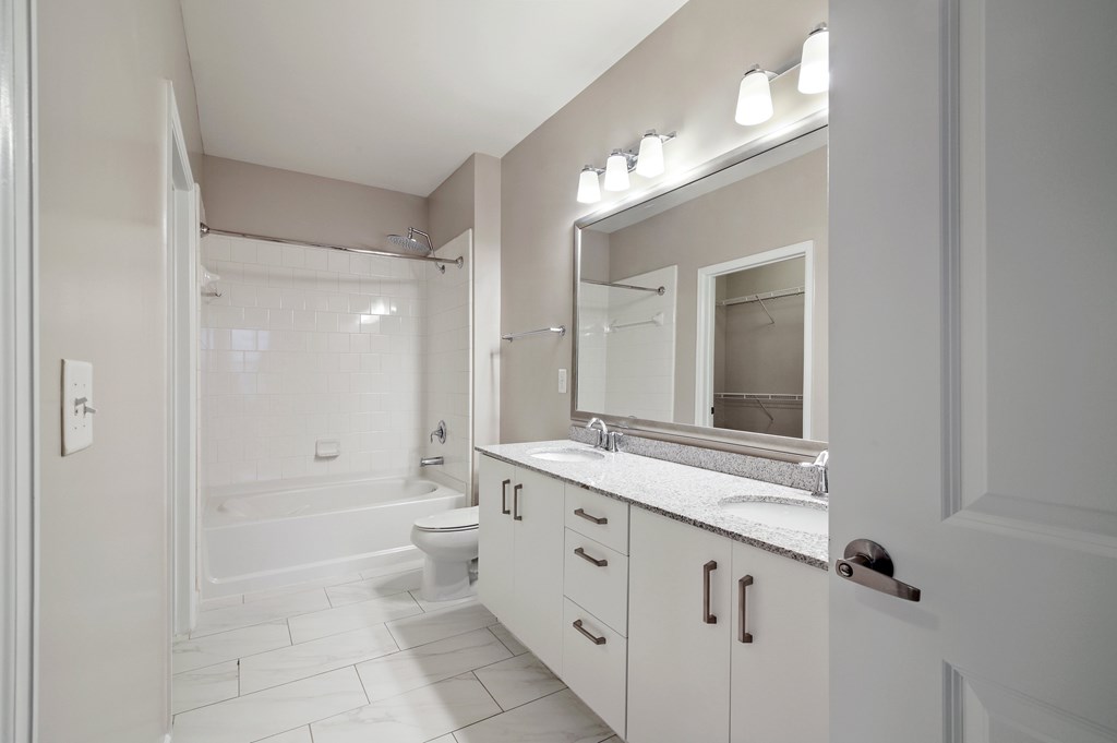 A white bathroom with a tub, sink, and mirror.