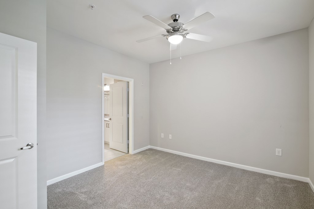 A room with a ceiling fan and carpeted floor.
