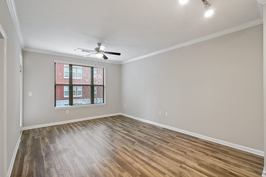 A room with a ceiling fan and a window with a view of a building outside.