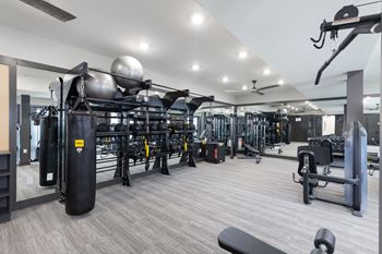 a gym with weights and cardio equipment on the floor and a ceiling fan
