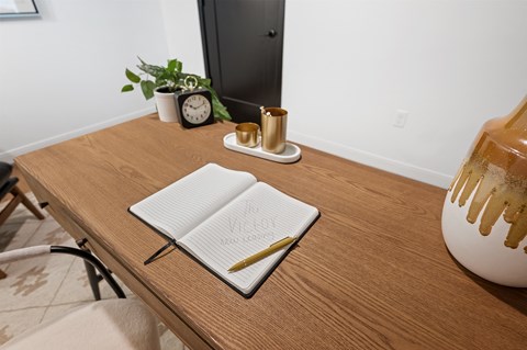 a desk with a notebook and pen on it