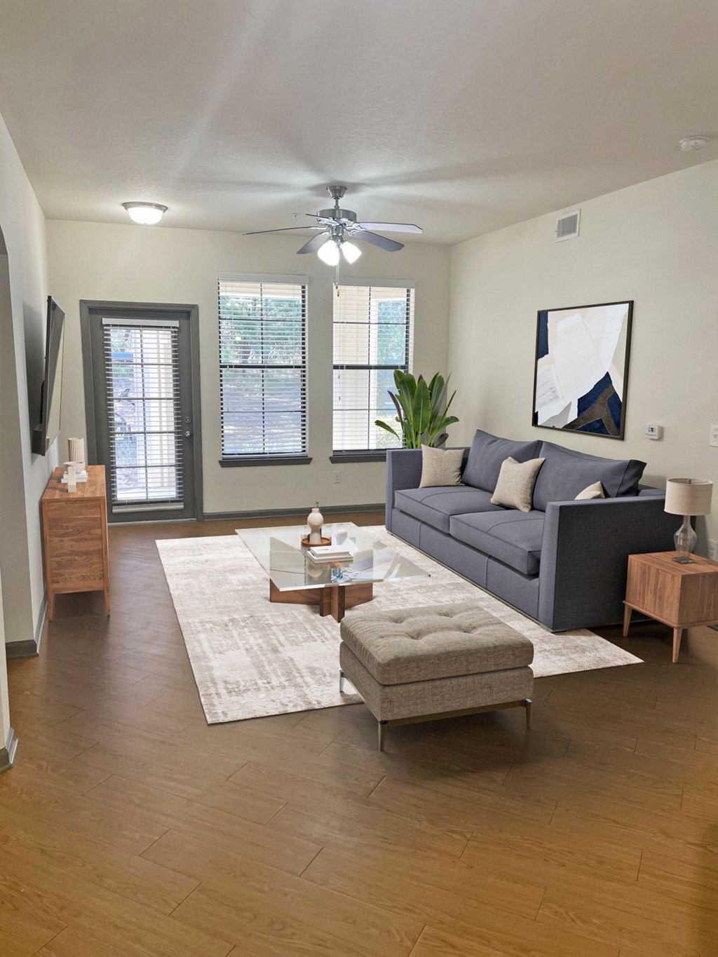 A living room with a grey couch, a coffee table, and a ceiling fan.