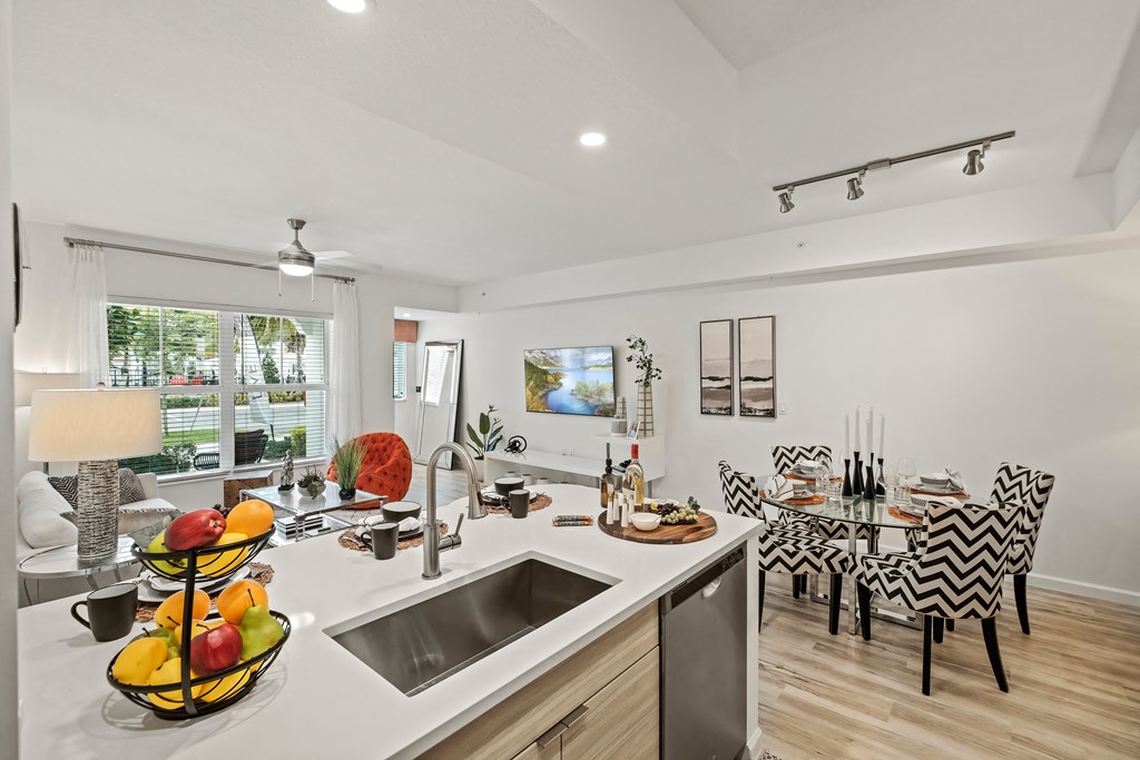 a kitchen with a sink and a counter top next to a living room with a table and at Altis Grand Lake Willis, Orlando, 32821