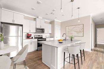 A modern kitchen with a white island and bar stools.