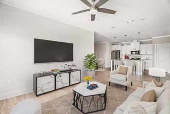 A living room with a white couch, a coffee table, and a flat screen TV mounted on the wall.