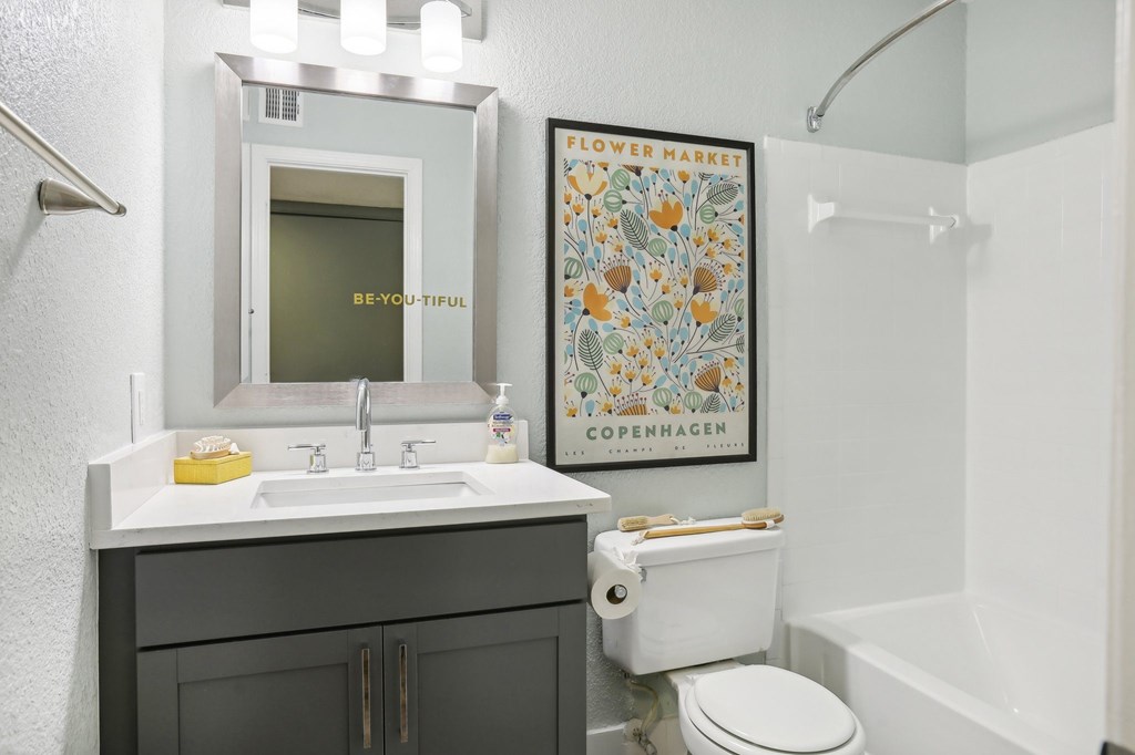 A bathroom with a toilet, sink, and poster.