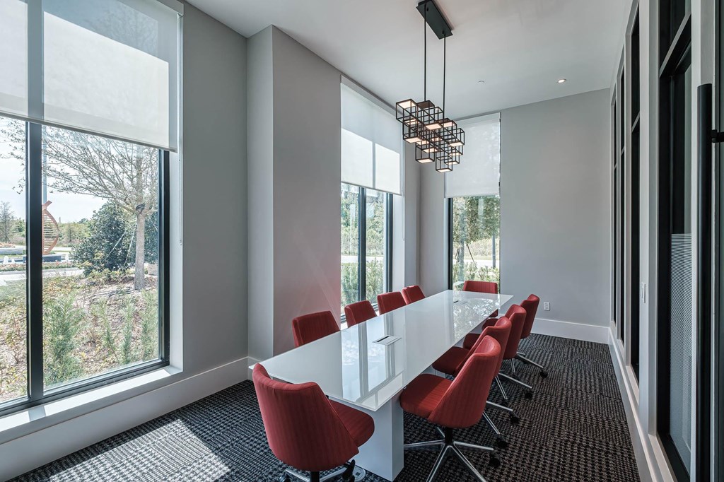 a conference room with a long white table and red chairs