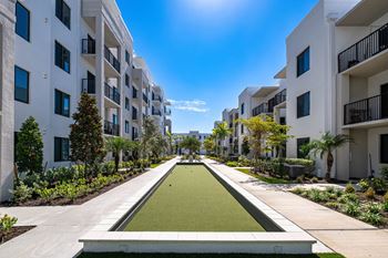 A sunny day at a residential complex with a green lawn in the middle.