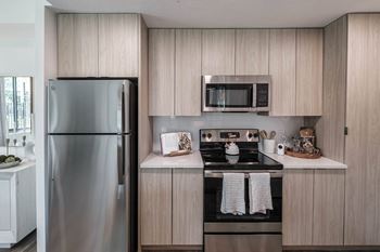 A modern kitchen with a stainless steel refrigerator and microwave above the stove at Altis Santa Barbara, Florida