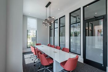 a long table with red chairs in a room with large windows at Altis Twin Lakes Apartments, Kissimmee, Florida