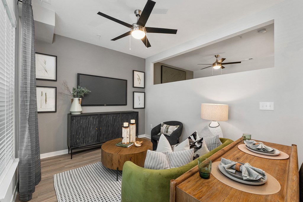 A living room with a ceiling fan, a couch, a coffee table, and a television.