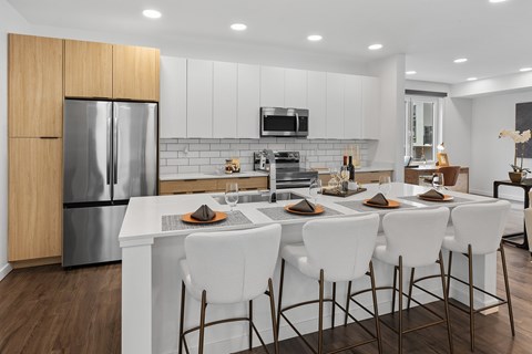 A modern kitchen with white chairs and a wooden cabinet.