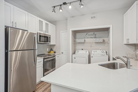 A kitchen with a stainless steel refrigerator and white appliances.