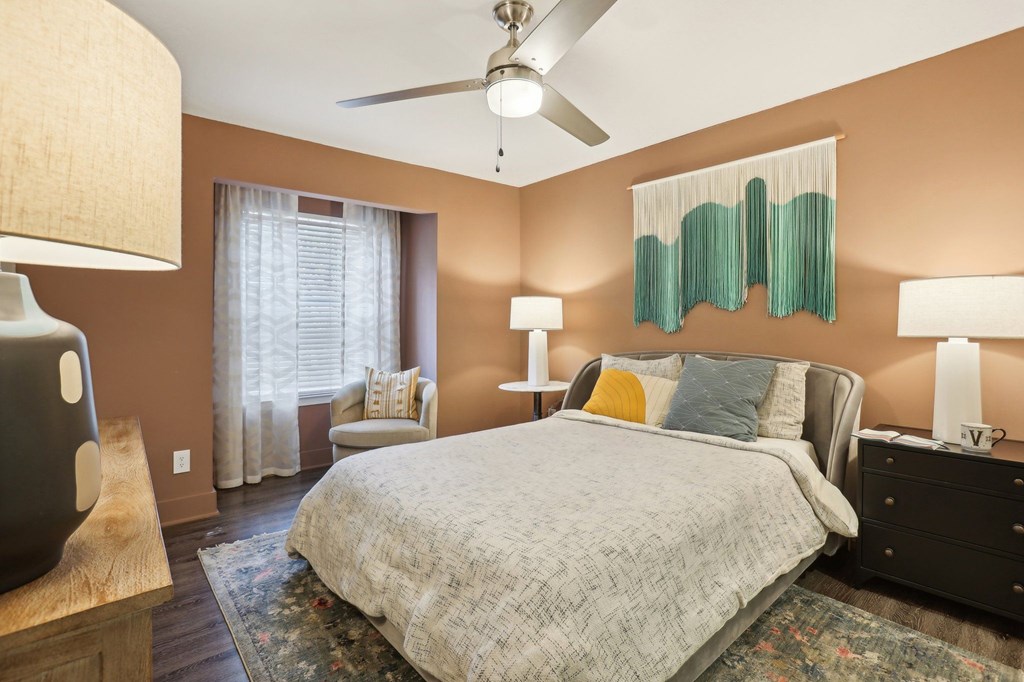 A bedroom with a bed, dresser, and ceiling fan.