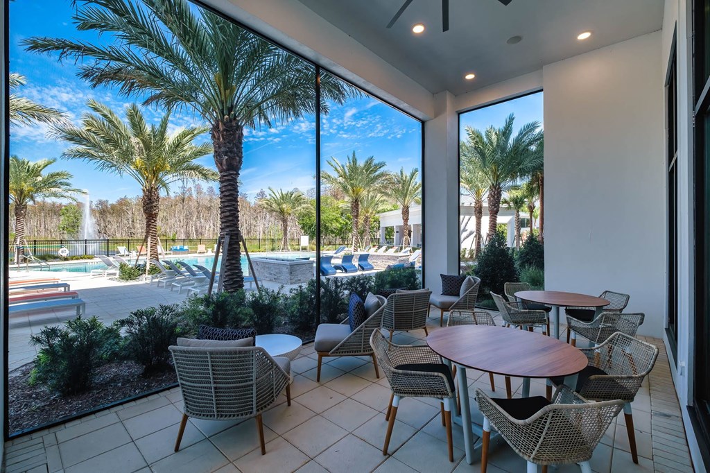 a patio with tables and chairs next to a swimming pool