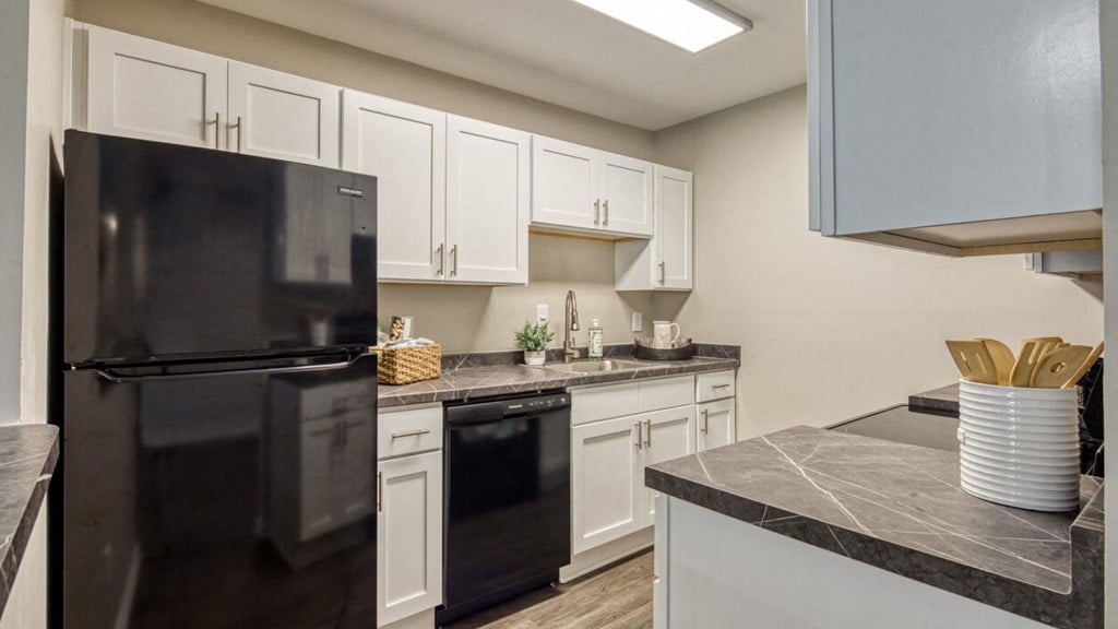 a kitchen with white cabinets and black appliances