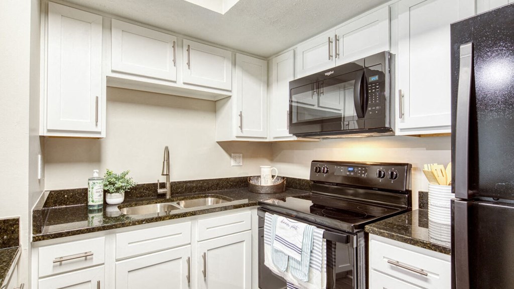 a kitchen with white cabinets and black appliances