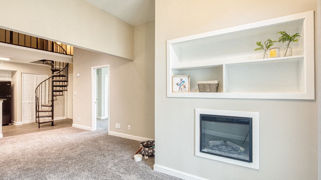 a living room with a fireplace and a staircase in the background