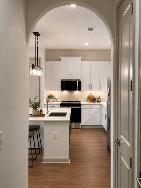 A kitchen with white cabinets and a wooden floor.