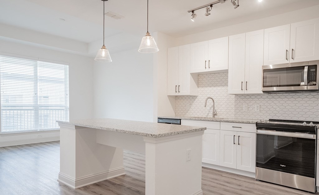 an empty kitchen with white cabinets and a counter top