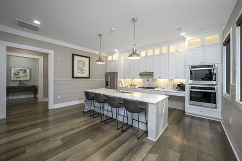 a kitchen with white cabinets and a large island with three chairs