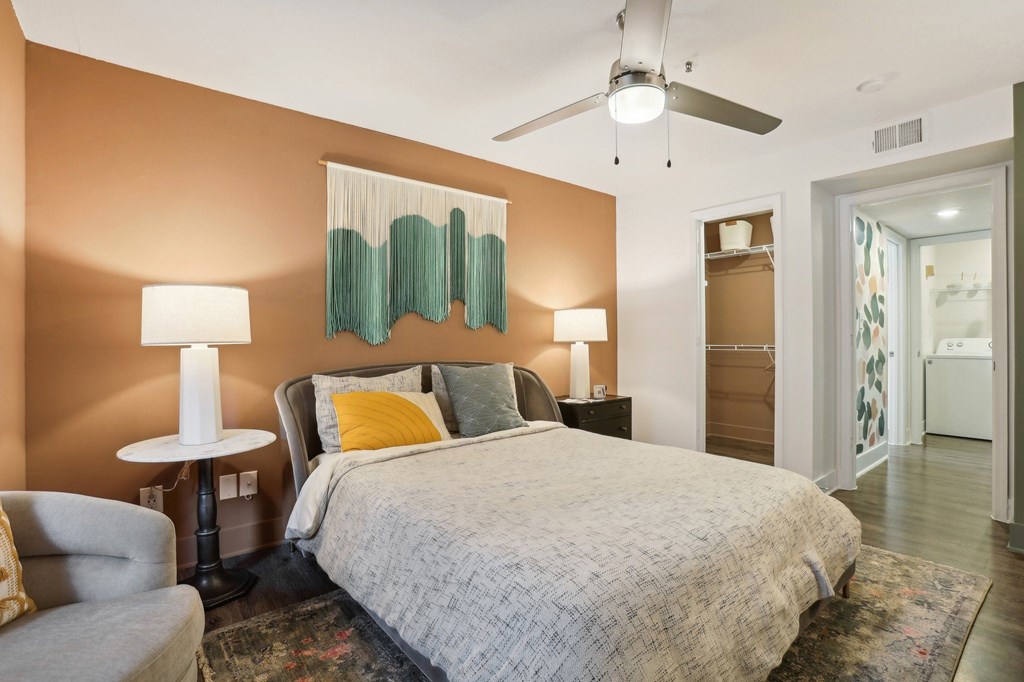 A bedroom with a bed, chair, and two lamps.