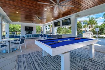a pool table in a covered patio with tables and chairs at Altis Twin Lakes Apartments, Florida