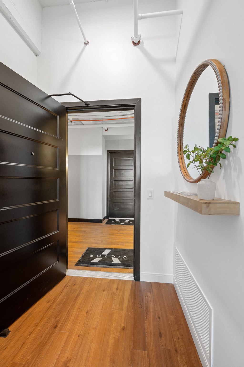 a view of a hallway with a black door and a mirror on the wall