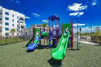 A playground with a blue and green slide and a red and blue play structure at Altis Santa Barbara, Florida