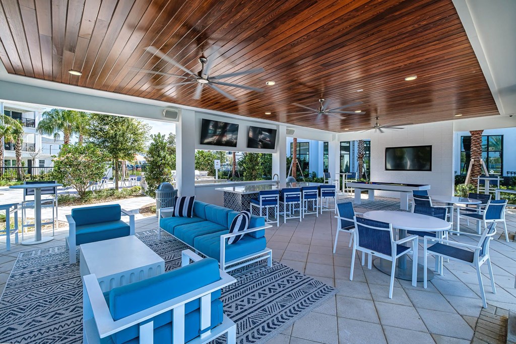 a lounge area with blue chairs and tables and a pool
