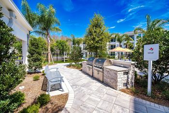 a patio with a grill and a bench next to a building at Altis Twin Lakes Apartments, Florida, 34744