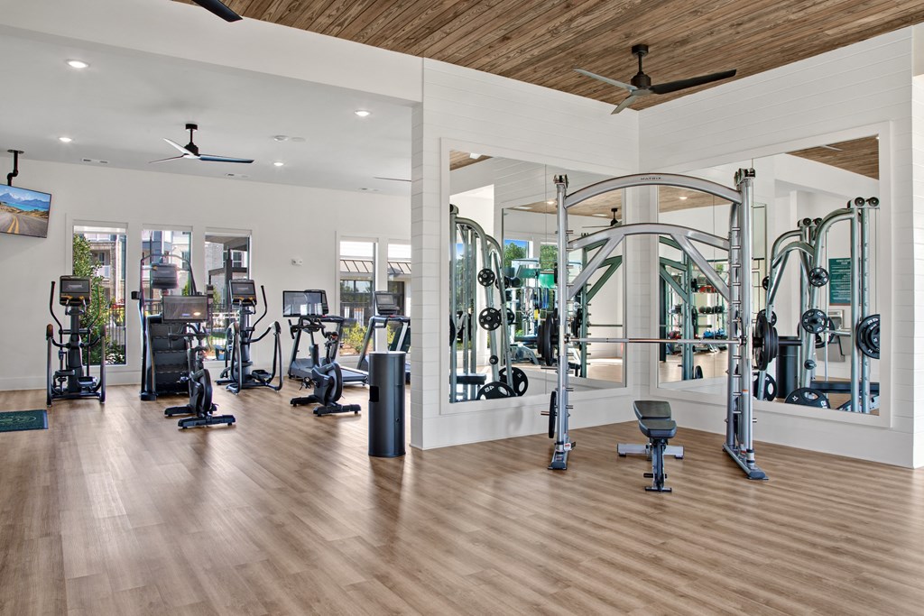 a large fitness room with cardio machines and weights