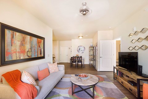 A living room with a grey couch and a painting on the wall.