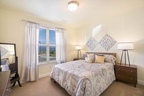 A bedroom with a large bed and a view of the outside through the window.