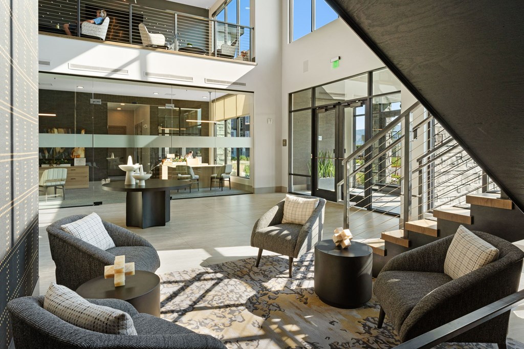 a living room with couches and chairs and a staircase