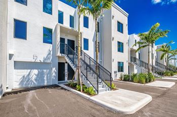 A white building with a black railing and a palm tree in front at Altis Santa Barbara, Florida