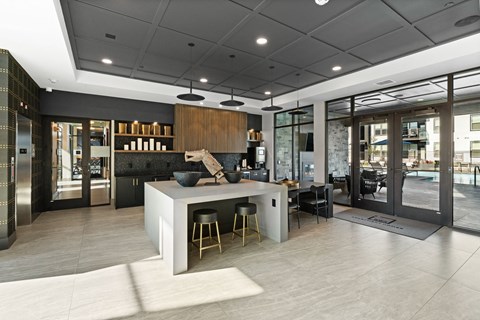 a large kitchen with a center island and chairs in a lobby