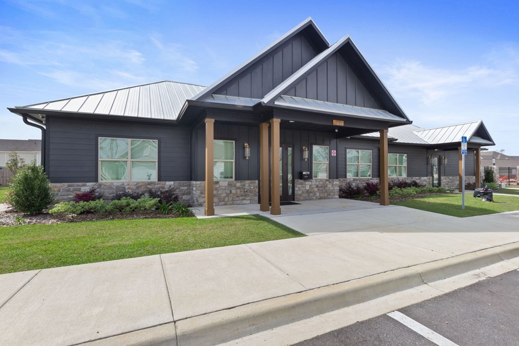the front of a gray building with a porch and a sidewalk