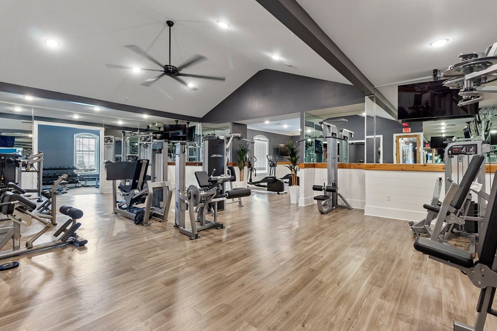 a gym with weights and cardio equipment and a tv on the wall
