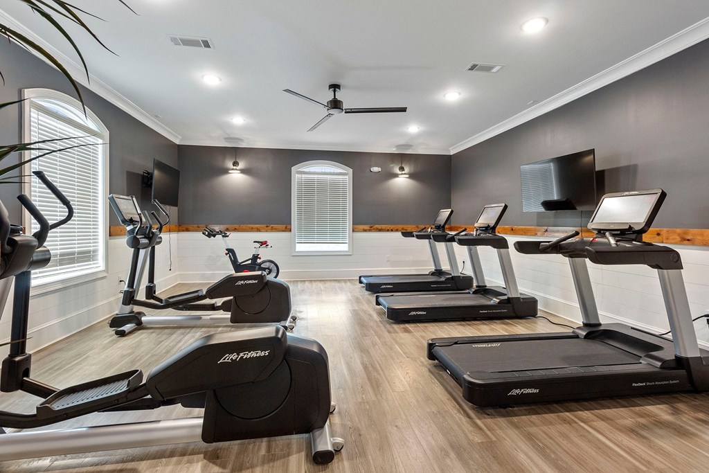 a gym with treadmills and weights and a tv