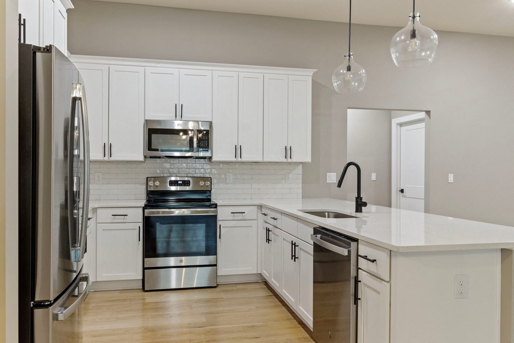 a large kitchen with white cabinets and stainless steel appliances